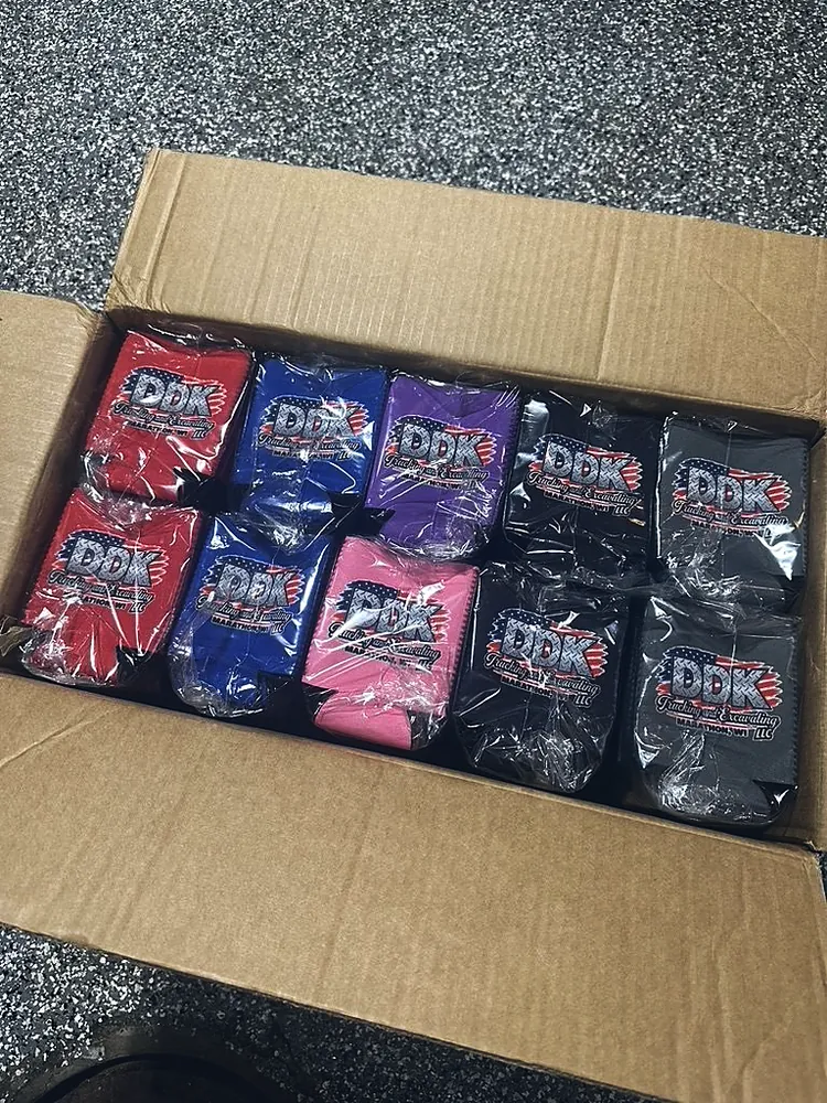 Box of custom printed can koozies in red, blue, purple, pink, black and gray with a DDK Trucking logo, promo products from Wausau, WI