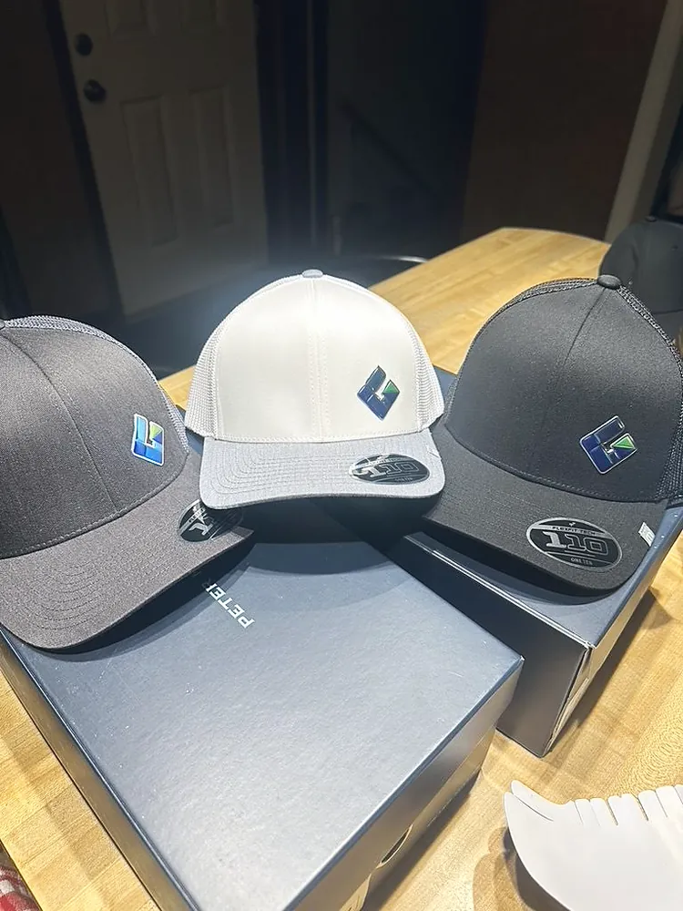 Three Flexfit caps in charcoal, white and black with a small metallic Gordon Aluminum logo, custom company hats from Wausau, WI