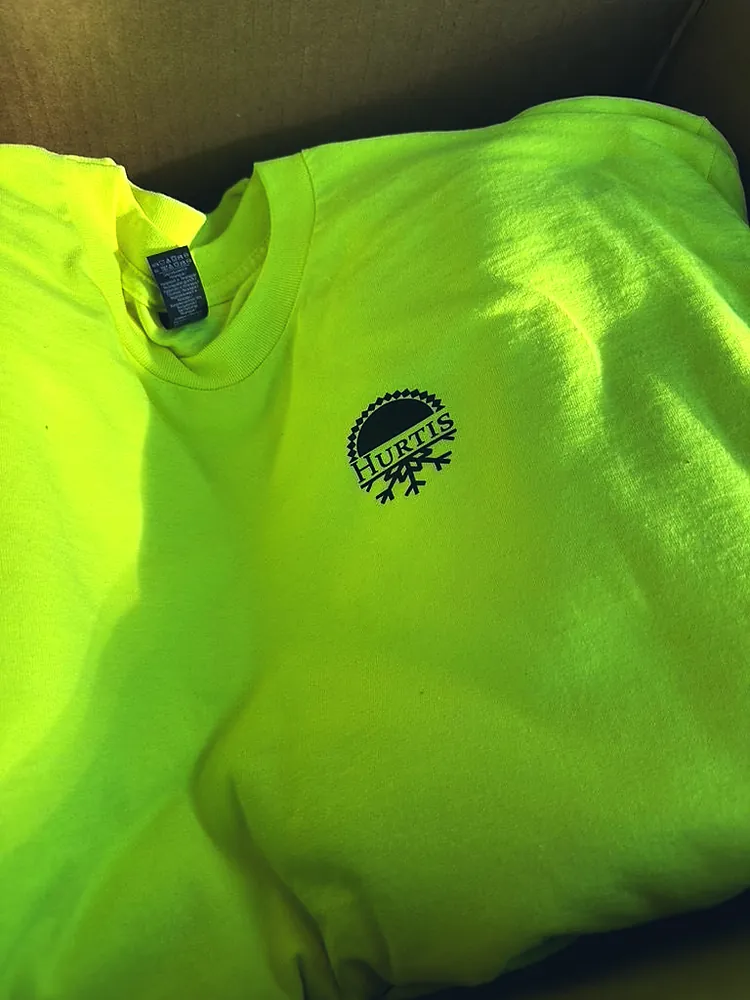 High-visibility yellow work t-shirt with a small black Hurtis logo printed on the left chest, custom work shirts from Wausau, WI