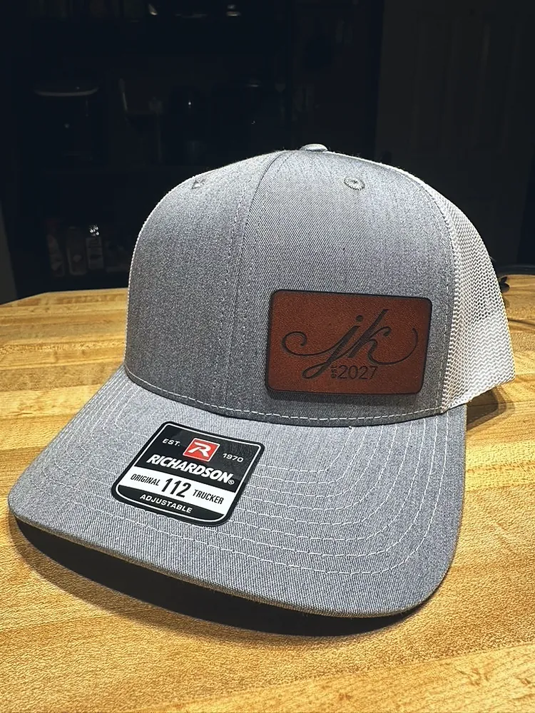 Gray and white trucker cap with an engraved leather patch monogram, custom leather patch hats from Wausau, WI