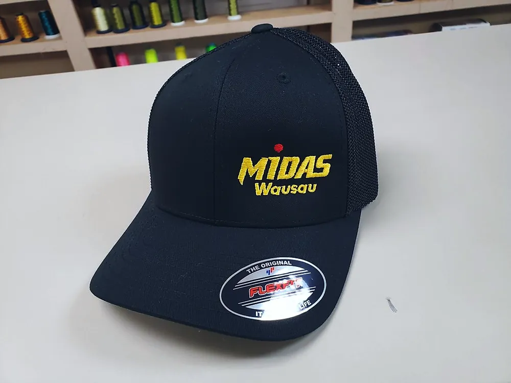 Black Flexfit cap with yellow embroidered Midas Wausau logo, custom embroidery by Patch Adams Promo in Wausau, WI