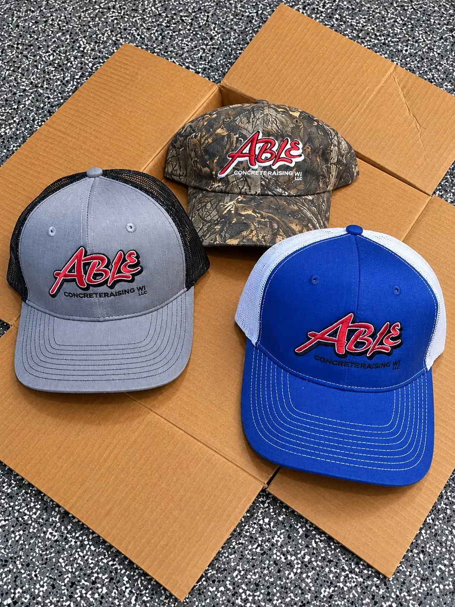 Gray, camo and royal blue trucker caps with raised embroidered Able Concrete Raising WI logo, custom hat embroidery in Wausau, WI