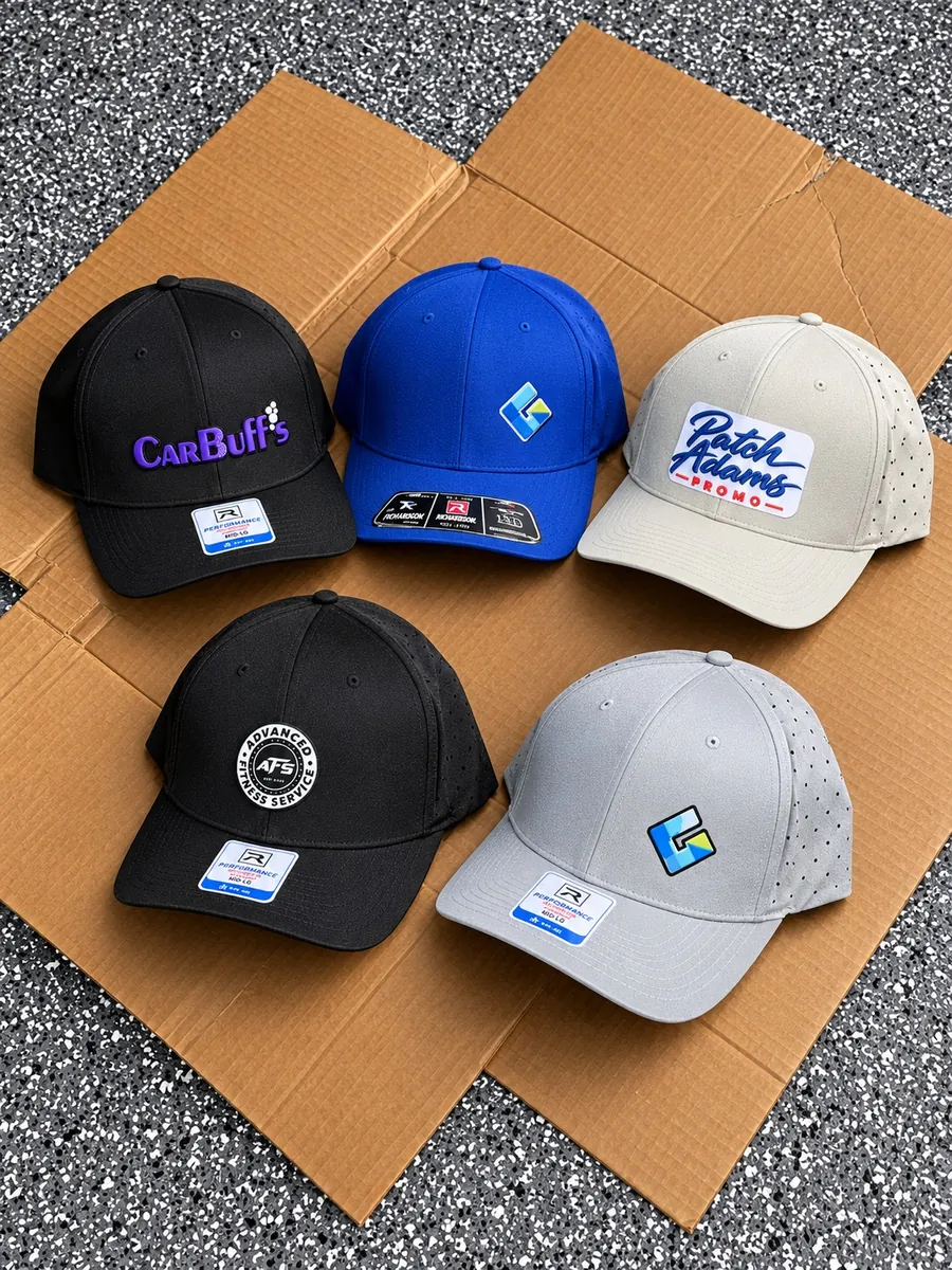 Five custom performance caps in black, blue, ivory and gray with logos for Patch Adams Promo, CarBuff's, Gordon Aluminum and Advanced Fitness, made in Wausau, WI