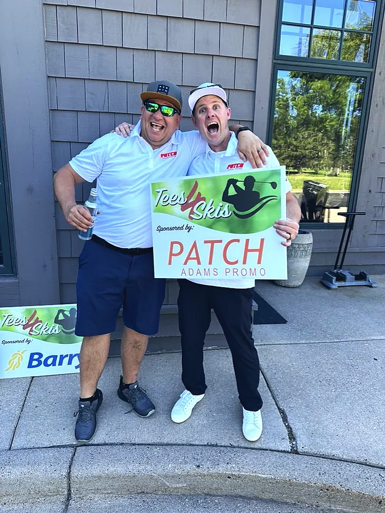 Two people holding a custom Tees 4 Skis golf outing sponsor sign made by Patch Adams Promo in Wausau, WI