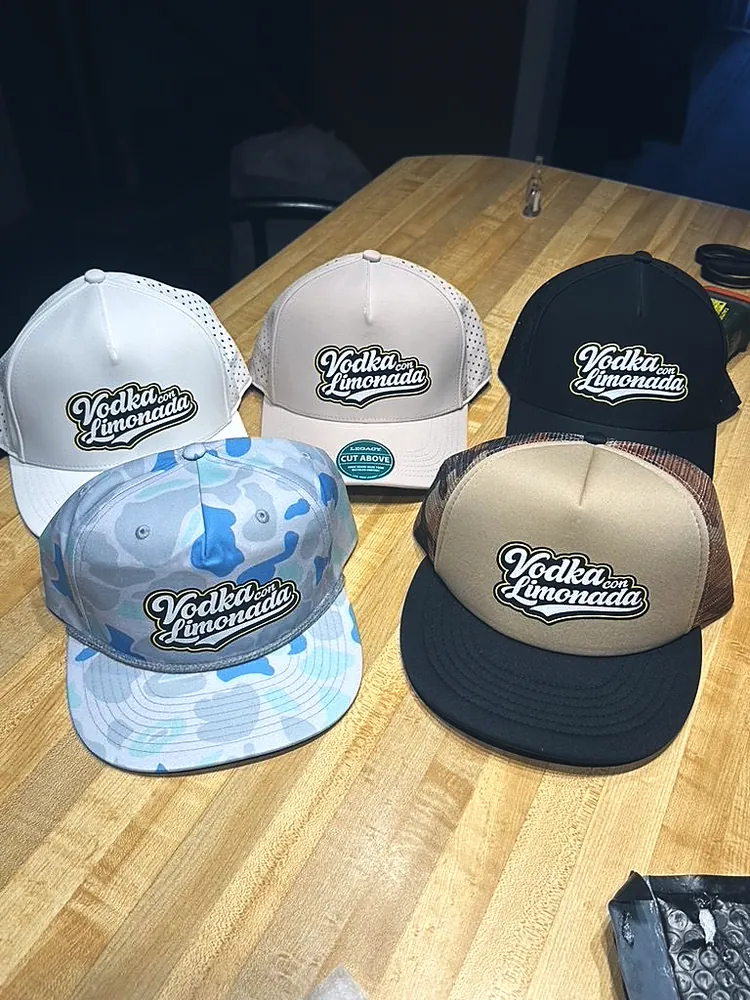 Five custom caps in white, tan, black, blue camo and foam trucker styles with the Vodka con Limonada logo, made in Wausau, WI